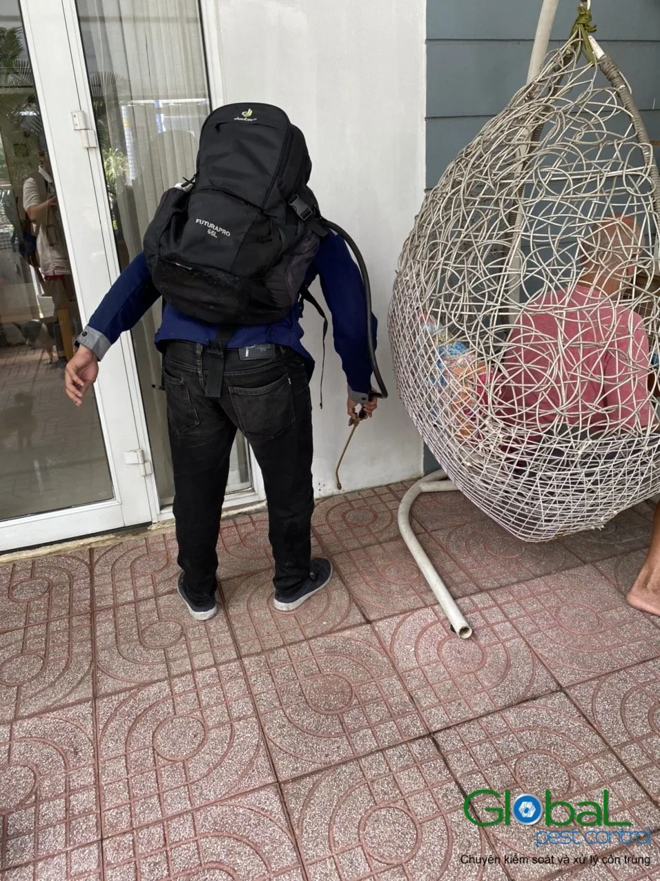 A technician with a backpack sprayer treating a shop entrance