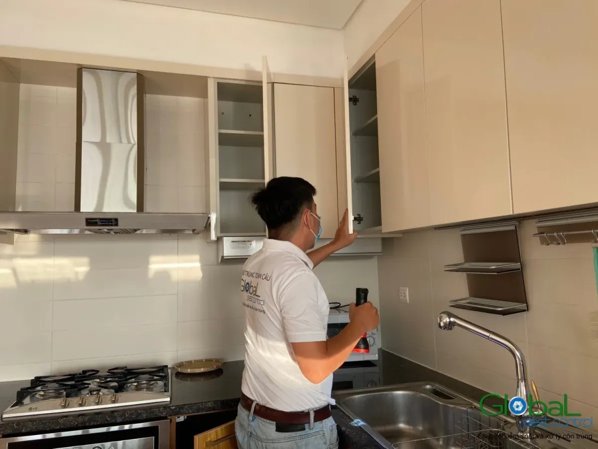 A technician checking wall-hung kitchen cabinets in an apartment