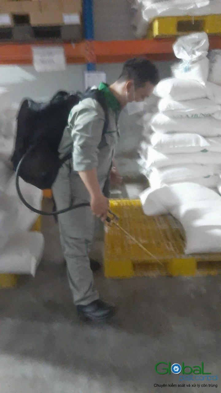 A technician treating around pallets of raw material sacks in a warehouse