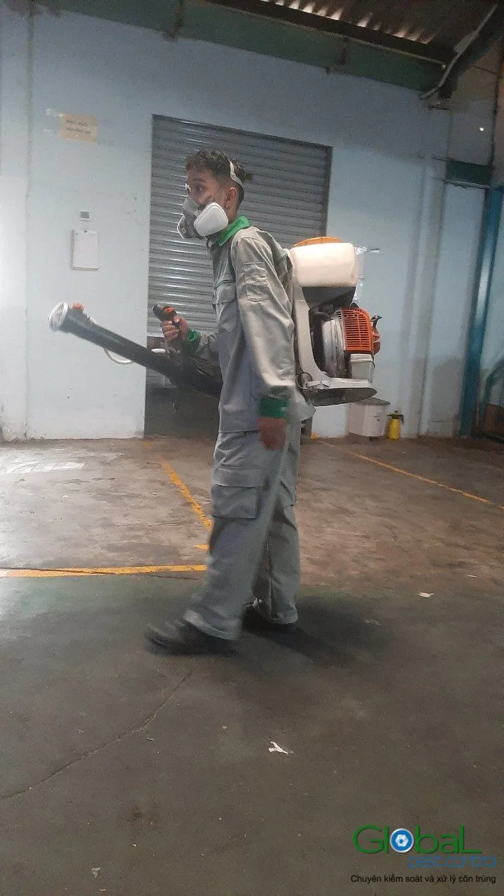 A technician cold-fogging a factory building with a roller door