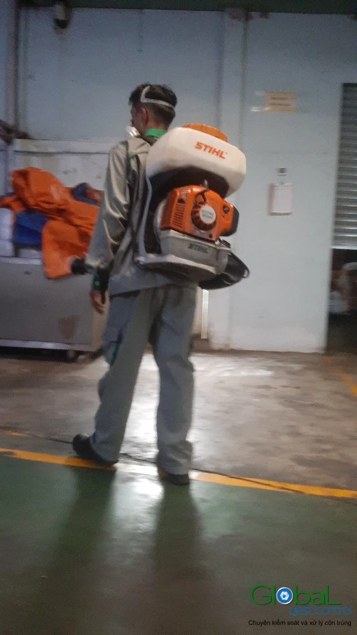 A technician using a motorised sprayer in a production area