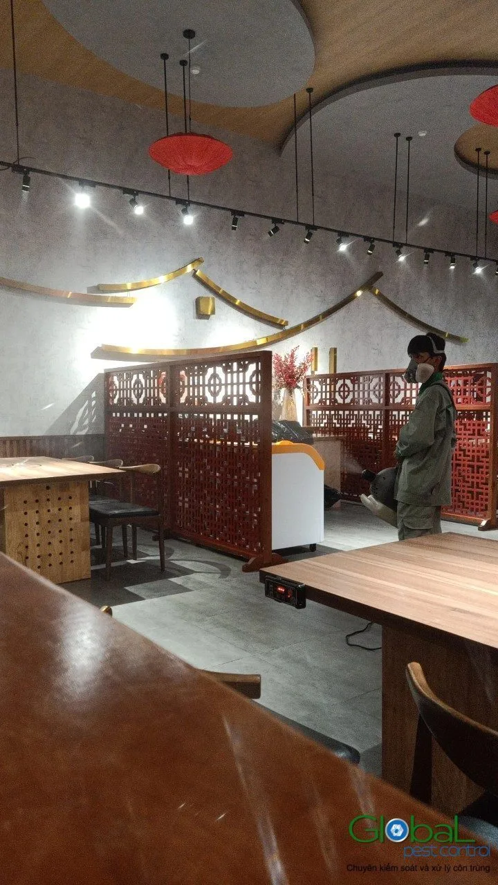 A technician treating the dining area of a restaurant outside opening hours