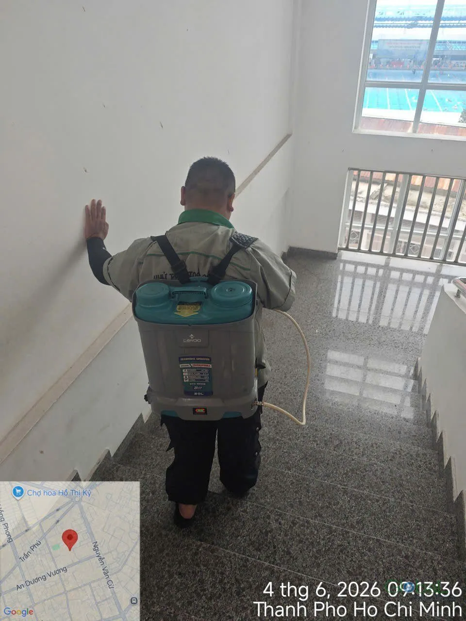 A technician with an electric sprayer treating a school stairwell corridor