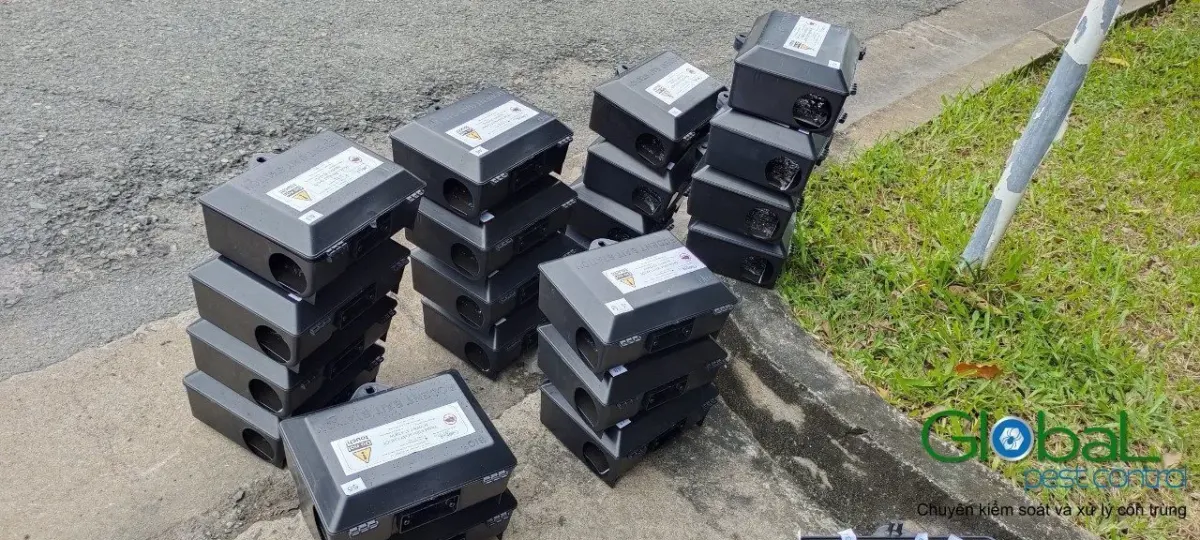 A stack of rodent bait stations ready to place along the grass outside a factory