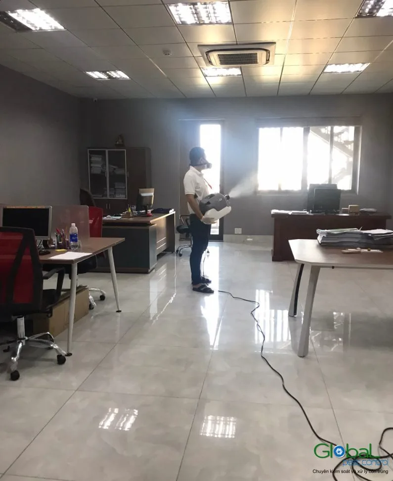 A technician treating an office with desks