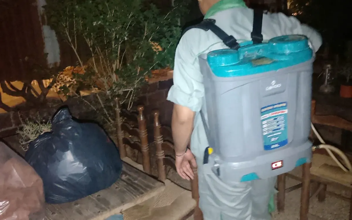 A technician treating the refuse area behind a restaurant