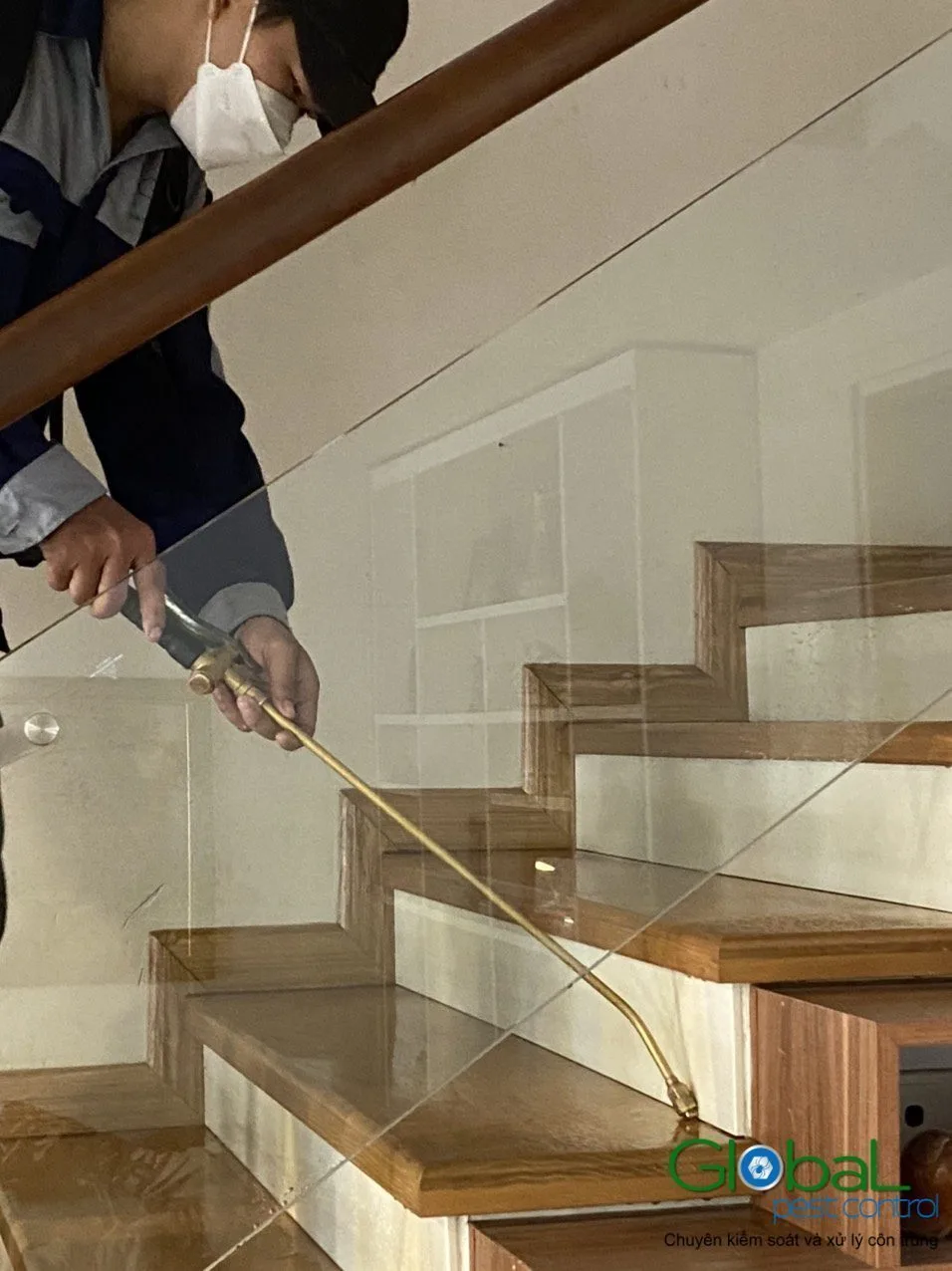 A technician treating along a wooden staircase in a shop