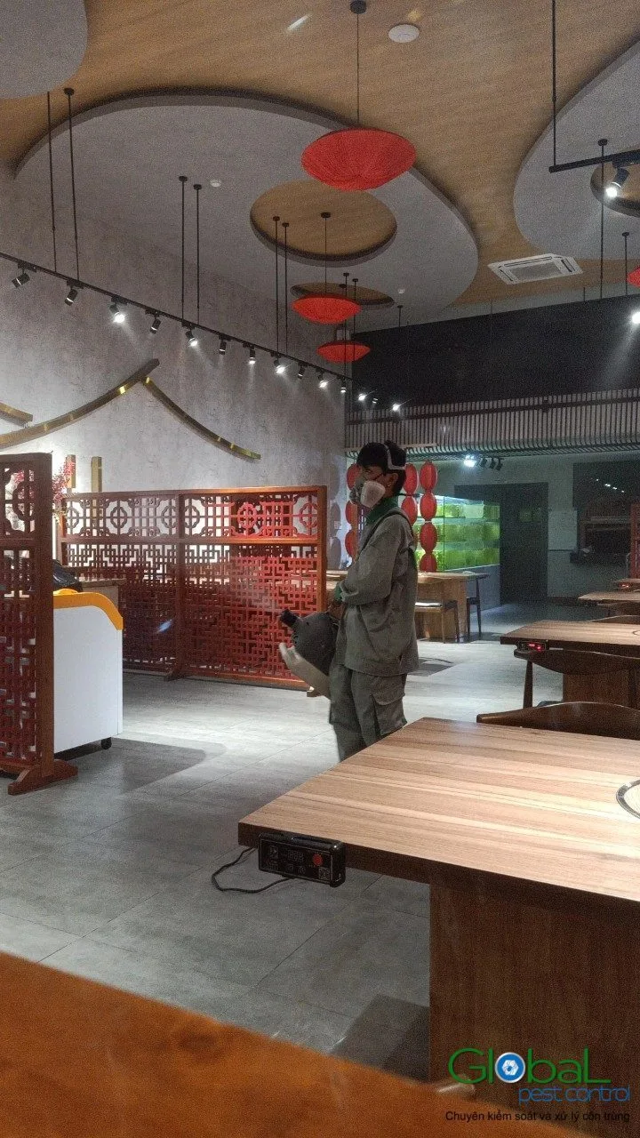 A technician treating a restaurant dining area before opening