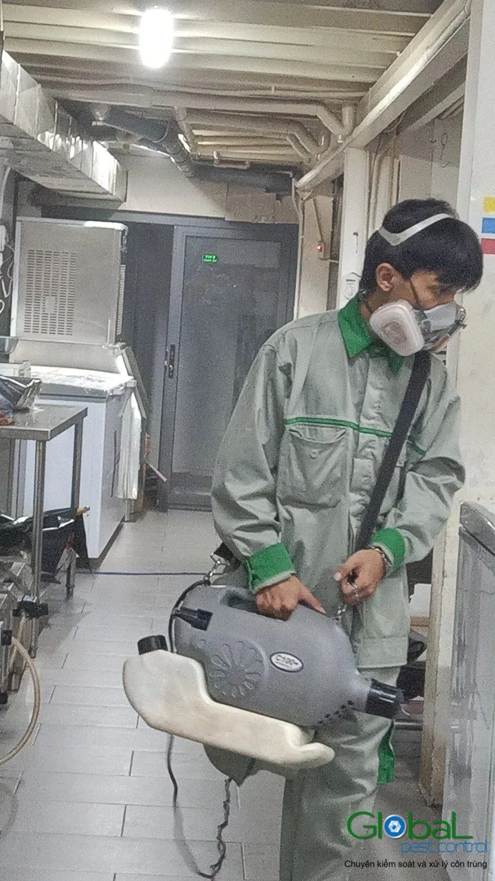 A technician in a respirator cold-fogging a kitchen