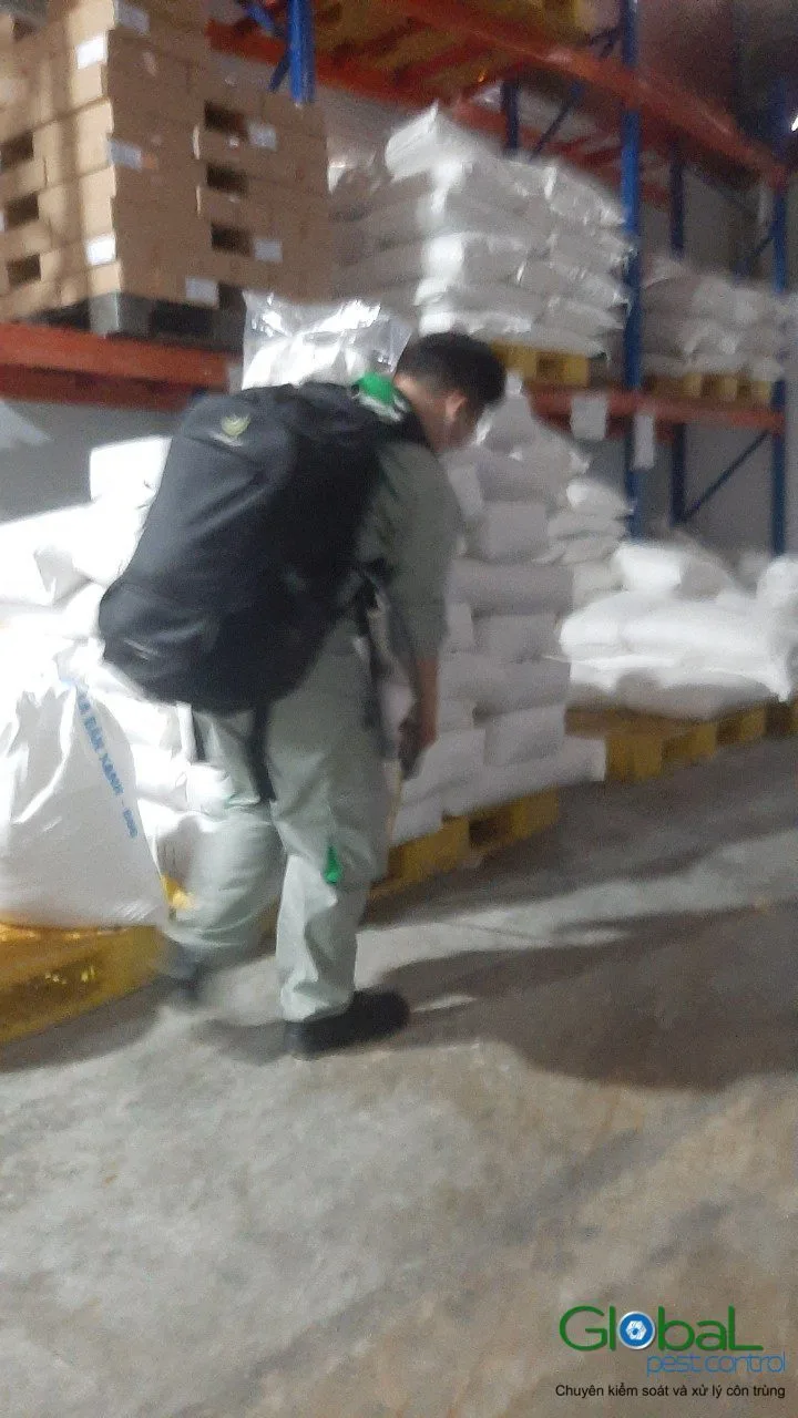 A technician treating beside pallets of raw material sacks in a warehouse
