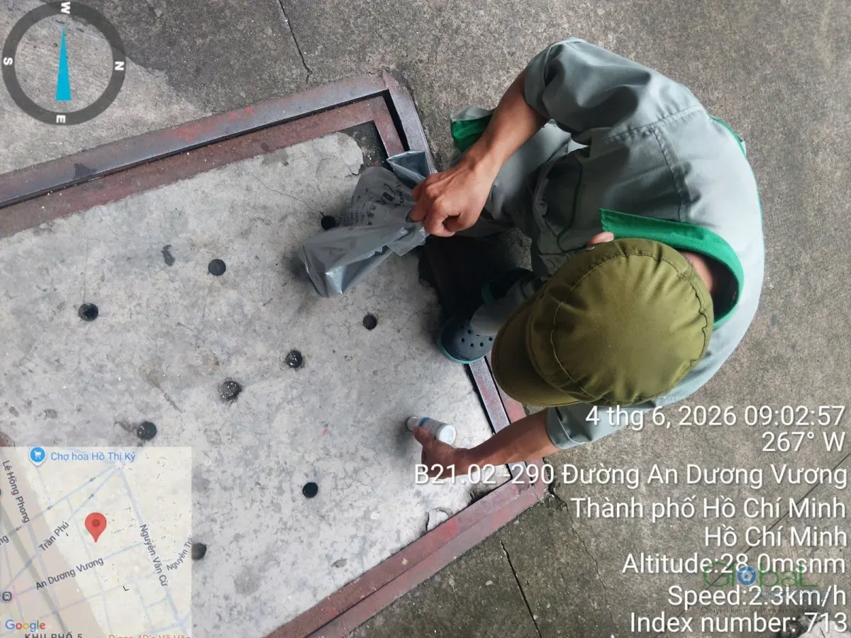 A technician placing cockroach bait in a school yard drain pit