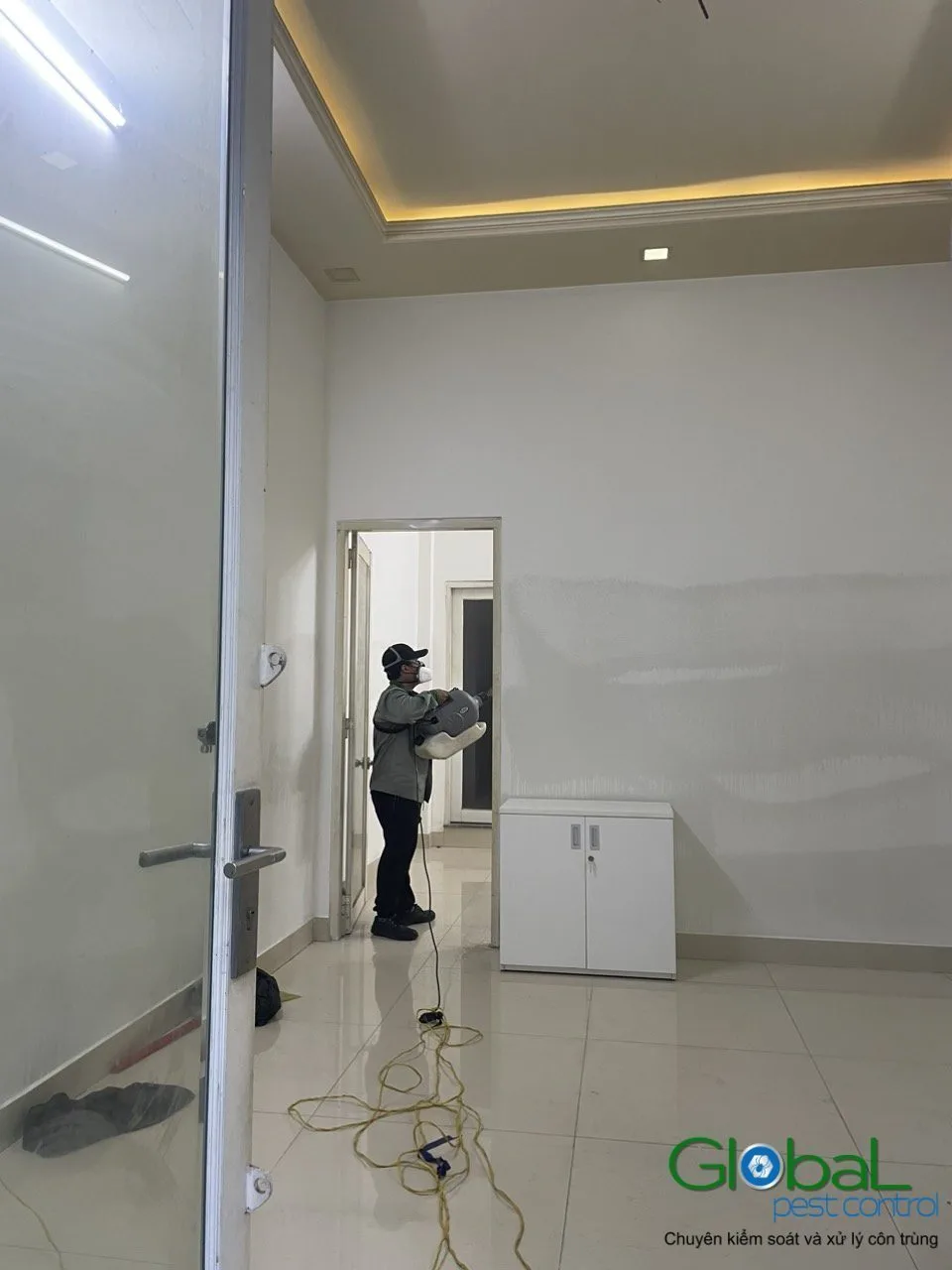 A technician treating an empty room with a wooden wardrobe in a home