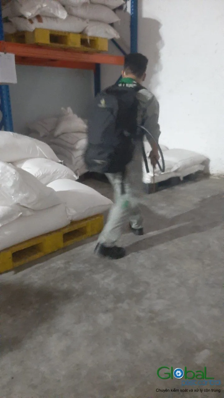 A technician treating along racks of raw material sacks in a warehouse