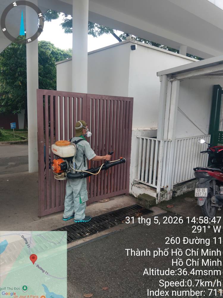 A technician with a mist blower treating the area inside a driveway gate