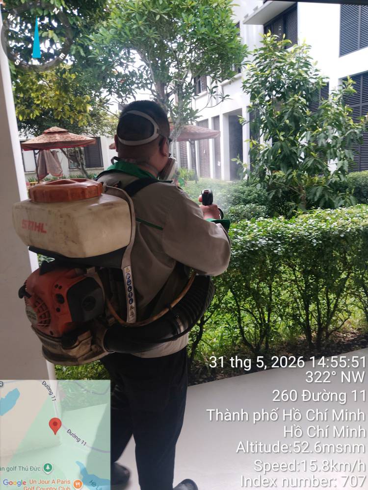 A technician moving along a building exterior with a backpack mist blower