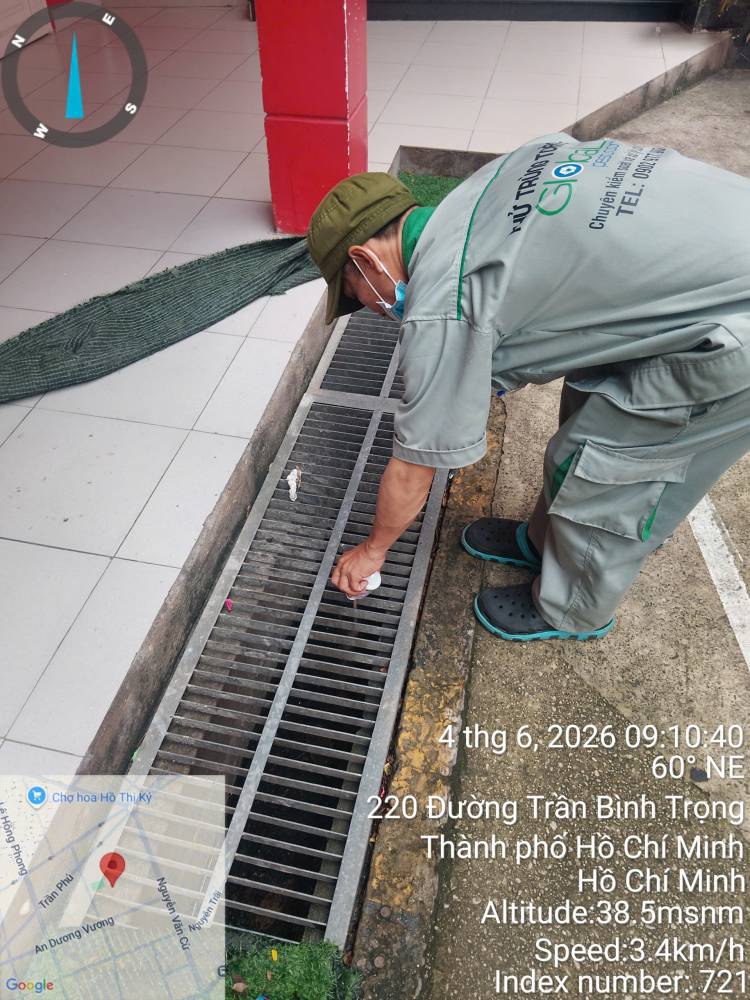 A technician lifting a drain grate and treating the gully beneath it