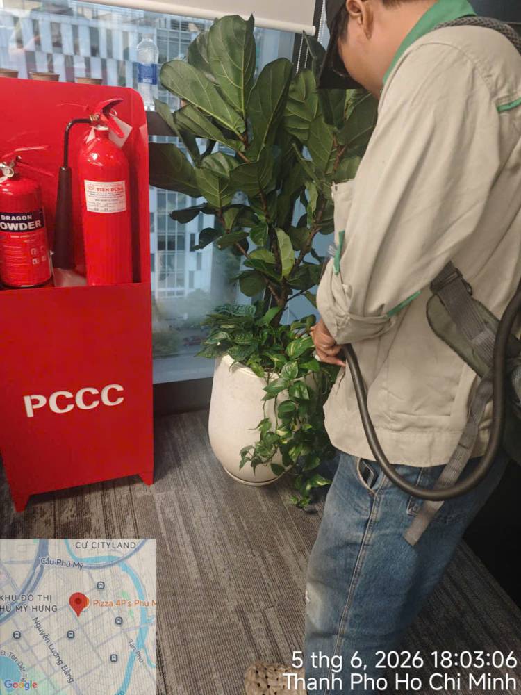 A technician treating indoor planters and pantry areas in an office