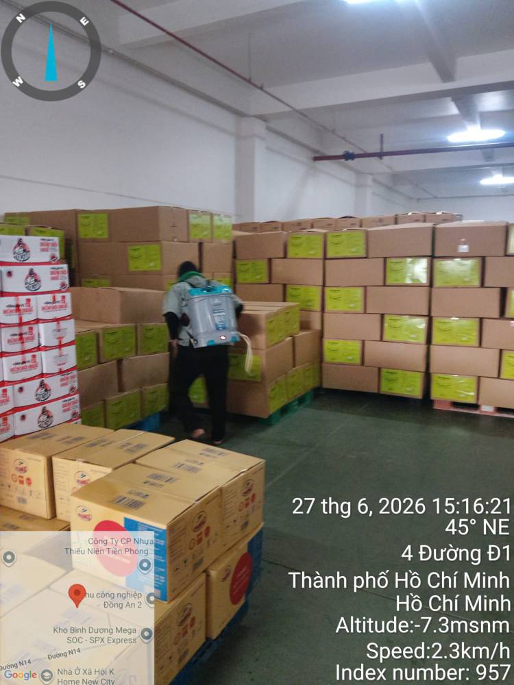 A technician treating stacked sacks and cartons in a warehouse