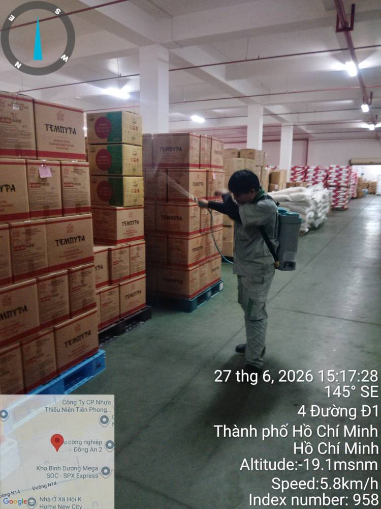A technician treating stacked sacks and cartons in a warehouse