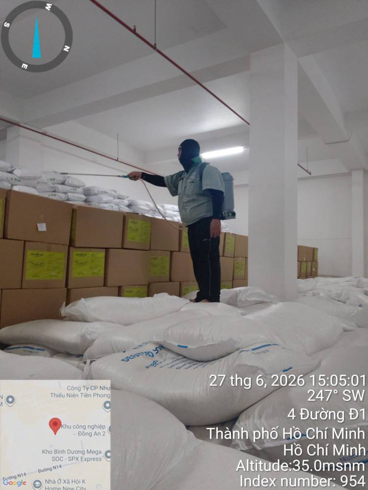 A technician treating stacked sacks and cartons in a warehouse