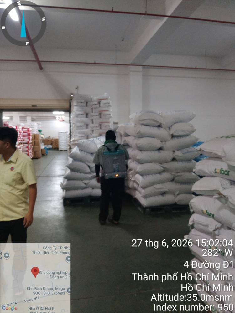 A technician treating stacked sacks and cartons in a warehouse