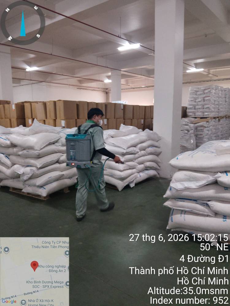 A technician treating stacked sacks and cartons in a warehouse