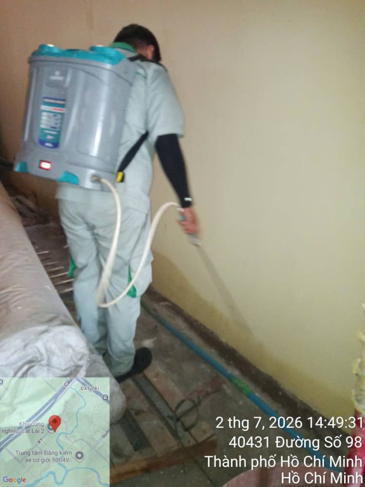 A technician treating stacked sacks and cartons in a warehouse