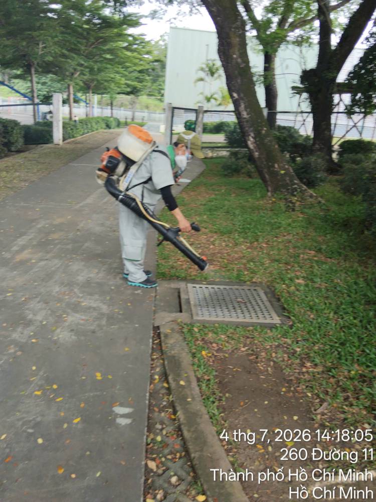 A technician treating outdoor paths, drains and planting at a school
