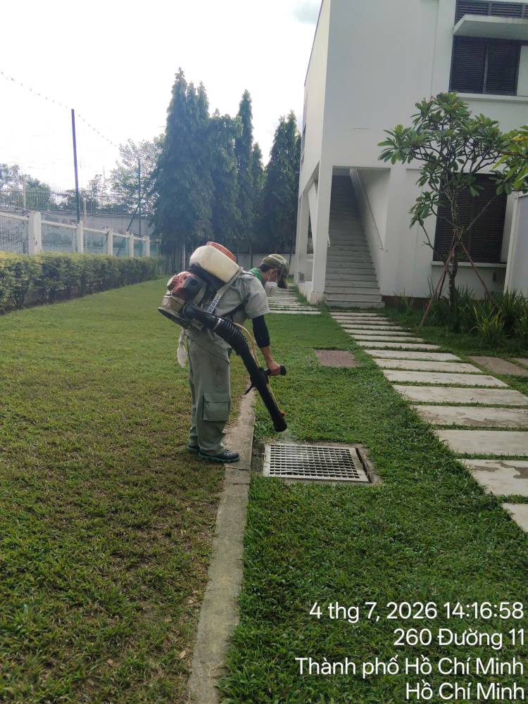 A technician treating outdoor paths, drains and planting at a school