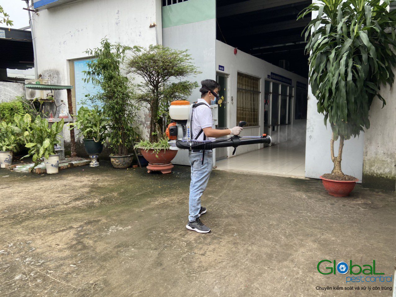 A Global Pest Control technician treating the entrance and lobby of a commercial building