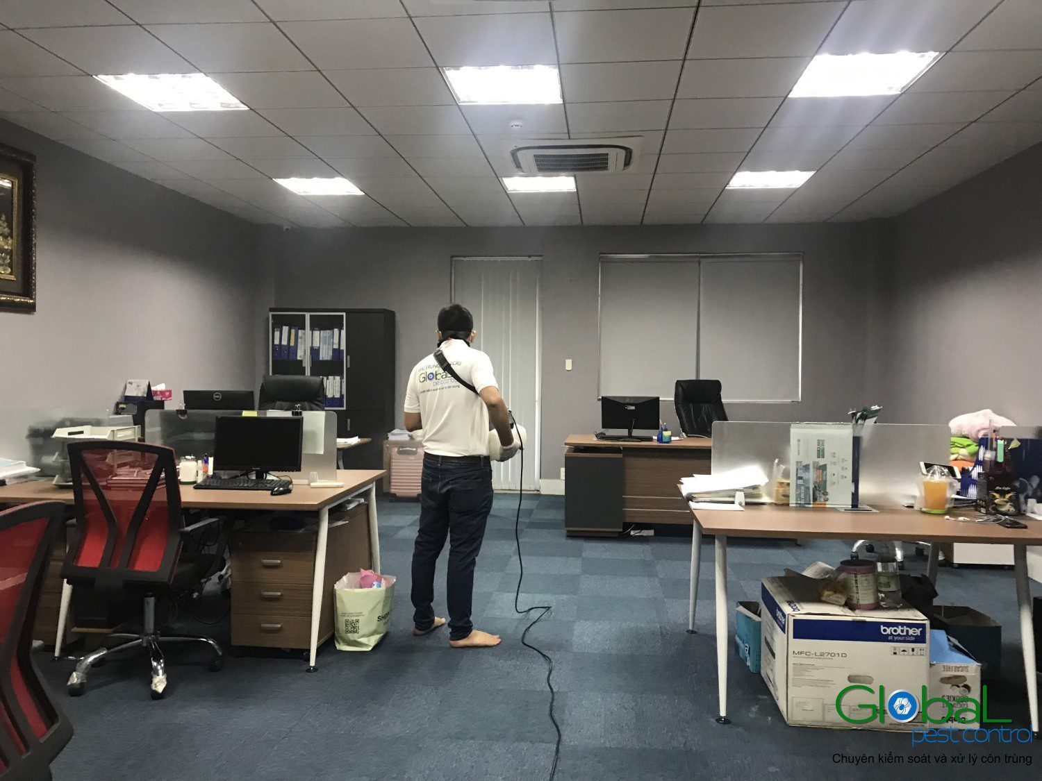 A Global Pest Control technician treating an occupied open-plan office